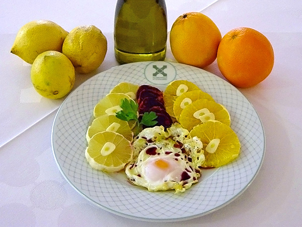 Plato tradicional: ensalada Hurdana con limón, naranja, huevo frito, chorizo y ajo.